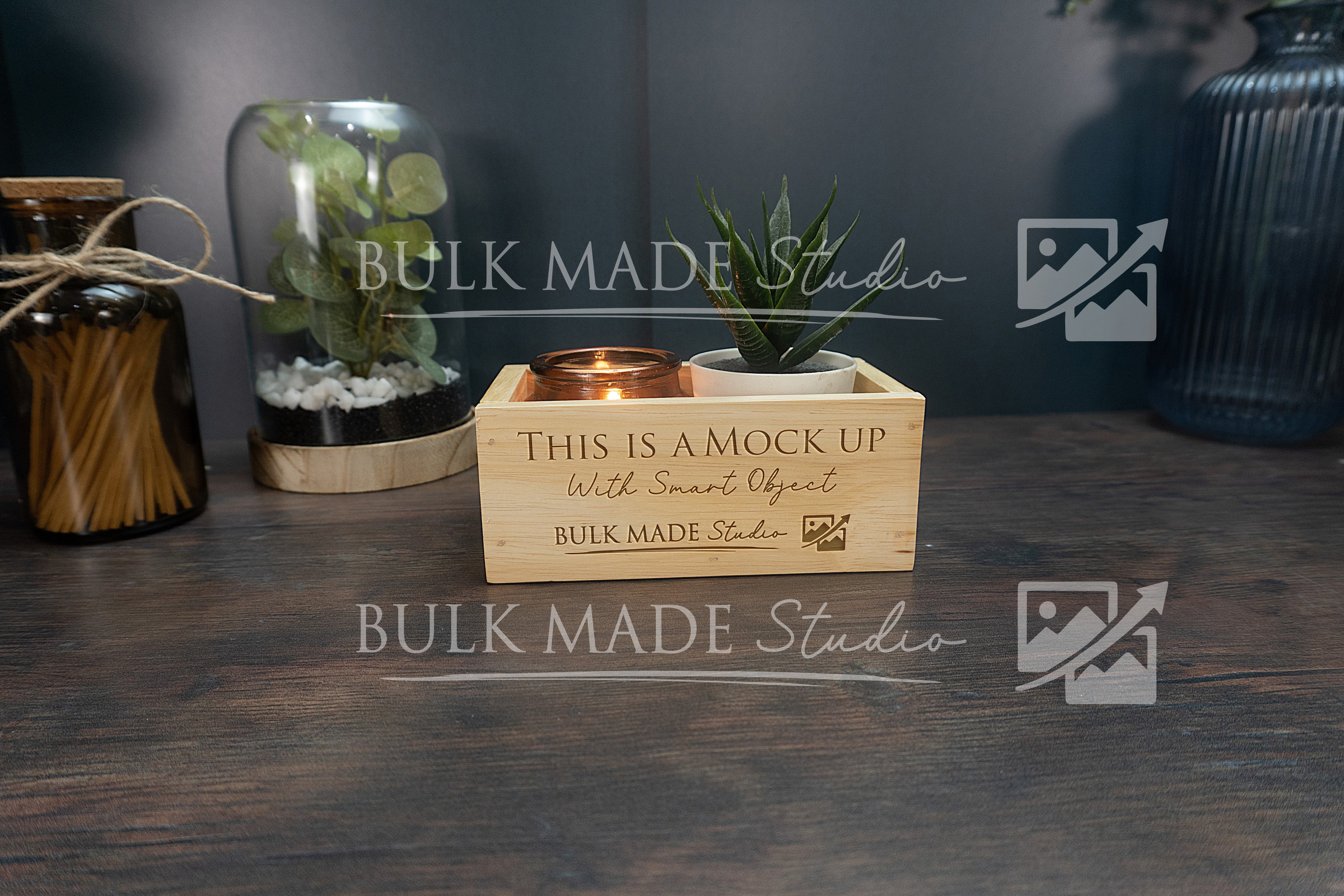Wooden box with a candle and plant on a dark surface, branded 'Bulk Made Studio'.
