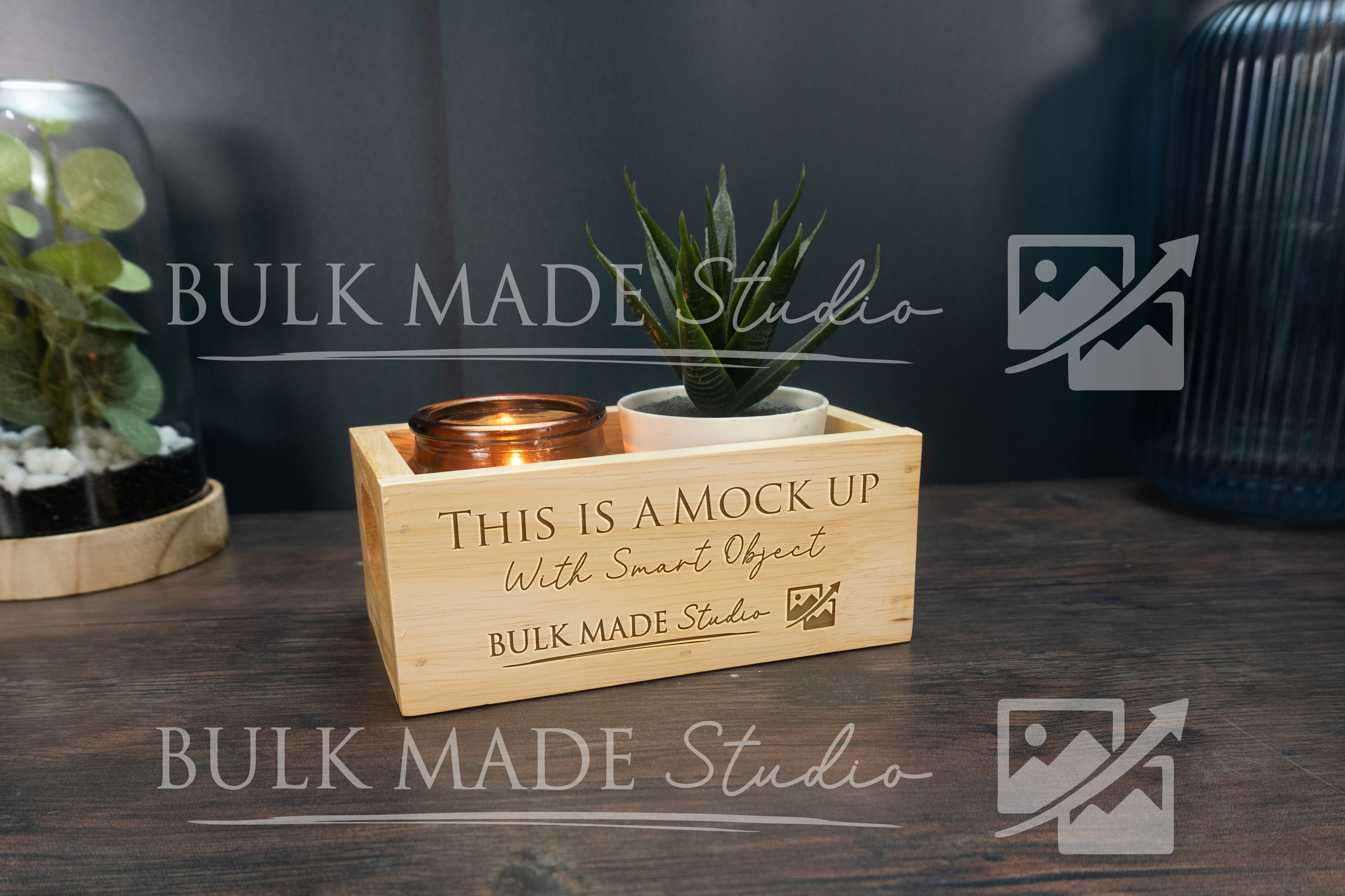 Wooden box with plant and candle on a dark surface, branded 'Bulk Made Studio'.